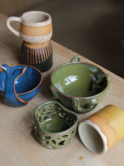 A creative collection of altered forms, including a pierced luminary and bowls with sculptural additions, showcasing the students' imaginative approach.