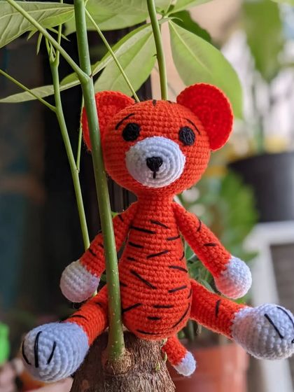 A friendly orange tiger with black stripes, sitting in a small houseplant.