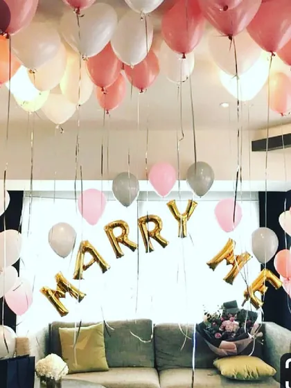 Balloons can be the centerpiece of a beautiful proposal. Here, I used gold "MARRY ME" foil balloons as the focal point, surrounded by soft pink, white, and silver latex balloons to decorate a living room space.