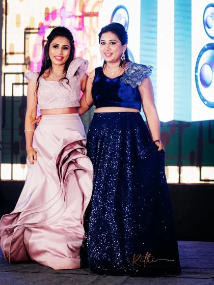 The bride and her sister posing at the sangeet, showcasing their coordinated custom outfits.