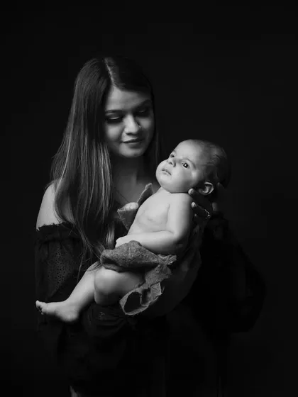 A mother gazes at her newborn in this classic black and white portrait. The simple composition emphasizes the powerful emotional connection between them.