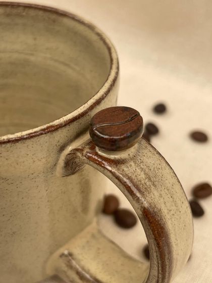 A collection of my handmade ceramic mugs, each with its own unique shape and glaze. The little coffee bean detail on the handle is a fun touch for coffee lovers.