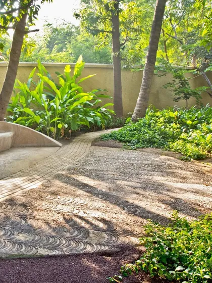 A detail from our Dumas House project, showing how we blend hardscape and softscape. The custom-patterned walkway flows organically into a seating area, surrounded by lush tropical foliage to create a tranquil and artistic garden path.