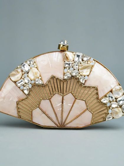 This fan-shaped clutch in a soft pink mother of pearl is perfect for a feminine and elegant look. It's embellished with clusters of sparkling stones and features a detailed brass fan design at its base.