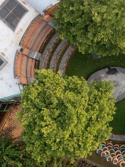 An aerial view reveals how green spaces are woven into the fabric of the campus. The amphitheater is surrounded by mature trees that were preserved during construction, providing shade and a constant connection to nature.