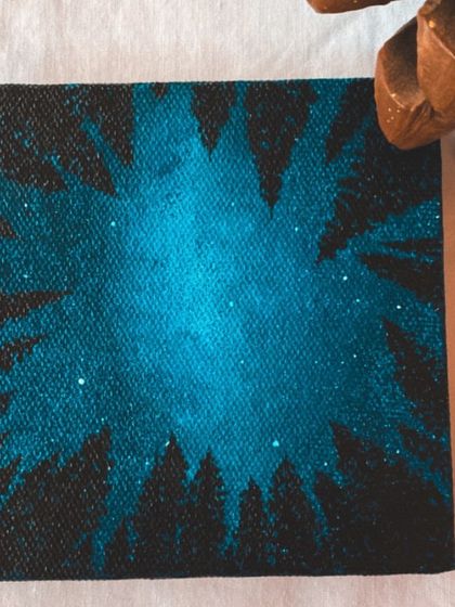 This mini-canvas painting of a starry night sky through pine trees is a beautiful small accent piece. It's inspired by travel photos and brings a sense of wonder to any small space.