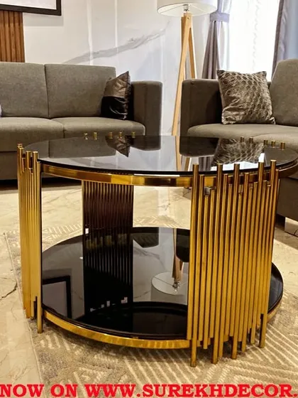 We design furniture that makes a statement. This elliptical center table features a sleek, two-tiered design with a black glass top and a striking gold electroplated steel base, offering both sophisticated style and practical surface space for your living area.