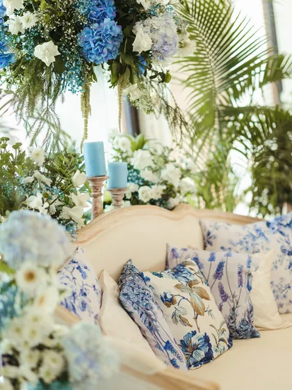 A close-up of a lounge sofa with custom-printed floral cushions that perfectly match the blue and white, chinoiserie-inspired theme.