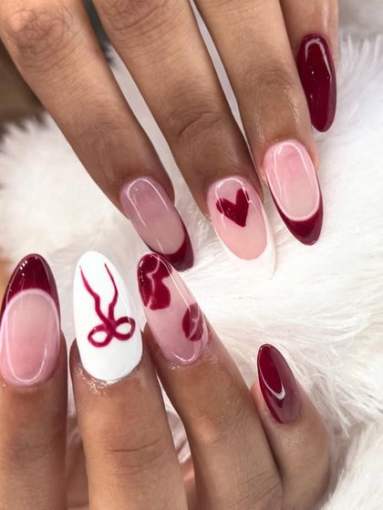A romantic and bold design, perfect for Valentine's Day. This set combines deep red nails with accent designs like a delicate bow, a tiny heart, and lips on a sheer or white base.