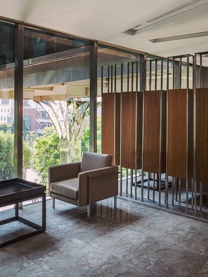 This shared reception space at the Stainless Steel Office features a custom stainless-steel partition with integrated wood panels. The design provides semi-privacy for the seating area while maintaining a connection to the surrounding office and views of the exterior courtyard.