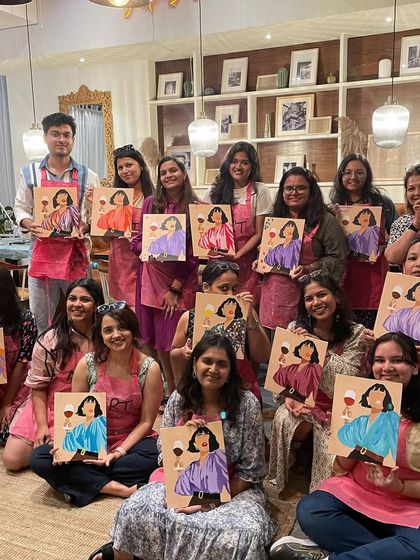 A large group from a public workshop, all smiles with their finished canvases. The sense of community is strong in these events.