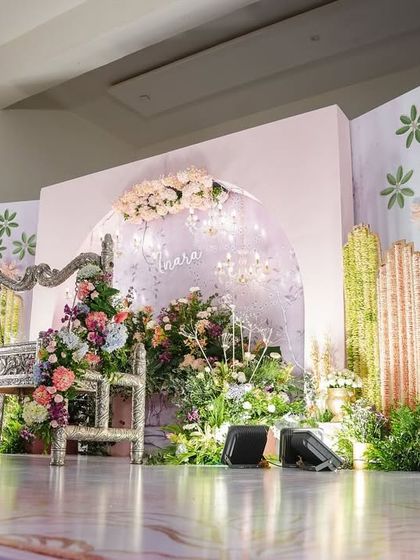 A wide view of the pastel-themed stage we designed for Inara's naming ceremony. The setup features an intricately carved silver cradle, a custom-printed floral backdrop, and elegant chandeliers, all combining to create a soft and dreamy atmosphere.