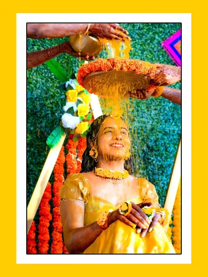 A beautiful shot of the bride being showered with turmeric and blessings. The vibrant yellow color and the bride's happy expression make this a perfect Haldi photo.