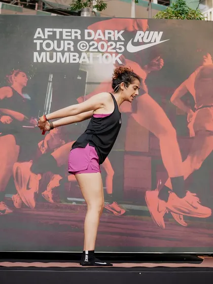 On stage, demonstrating a shoulder-opening stretch for the Nike After Dark Run Tour in Mumbai. Yoga is a perfect complement to running for mobility and recovery.