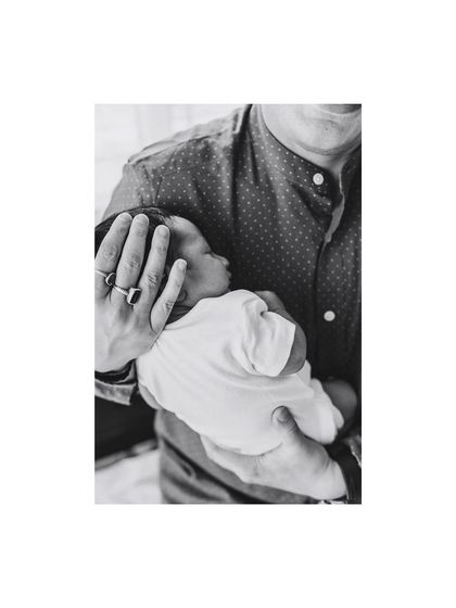 A father holding his sleeping newborn. This black and white image emphasizes the quiet, protective bond in a simple, powerful way.