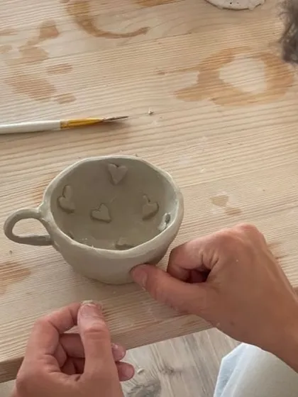 It all starts with a lump of clay and an idea. In our hand-building workshops, you can create something truly personal, like this mug being decorated with little hearts. It’s about making functional art that you can use every day.