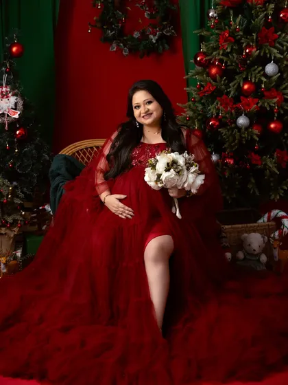 We can celebrate any season. This festive Christmas-themed maternity shoot uses a rich red gown and holiday decor to create a warm and magical portrait.