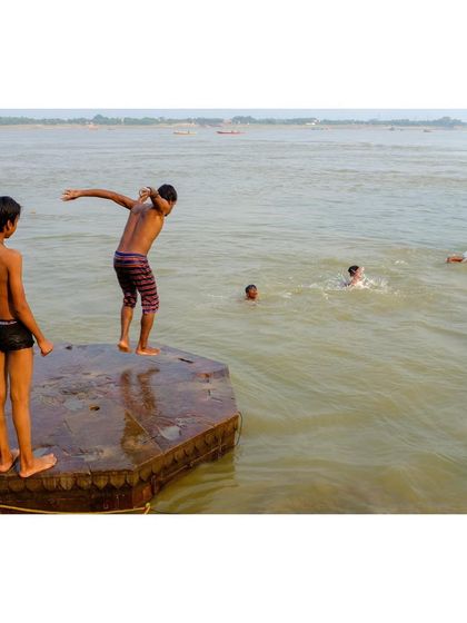 Boys jumping into the Ganga from a stone platform in Varanasi. This colorful image is full of life and action, capturing a classic scene of summer on the river.