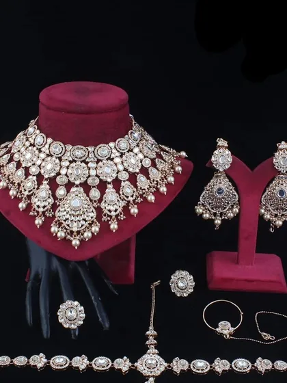 A complete bridal set in a champagne-gold tone, displayed with all its components: choker, earrings, maang tikka, nath, and hathphool.