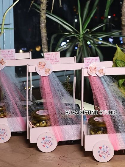 A side view of the luxury baby shower carts, showing the personalized notes and the mix of edible treats and keepsakes like the bonsai planter.