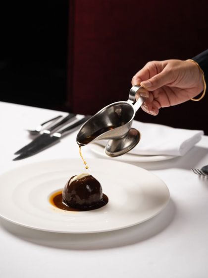 A study in contrast. The indulgent, rum-soaked Valrhona chocolate ball is presented alongside the ethereal Daulat ki Chaat, showcasing two entirely different moods in dessert.