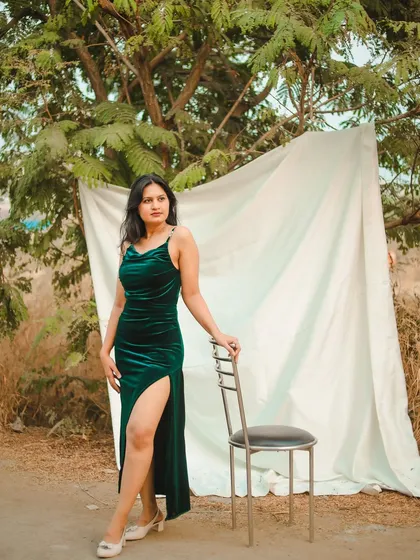 A full-length shot in a gorgeous green velvet dress. Using a simple white cloth as a backdrop outdoors creates a unique, high-fashion look.
