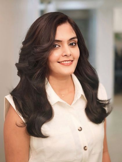 A happy client showing off her new voluminous brunette hairstyle, full of life and movement.