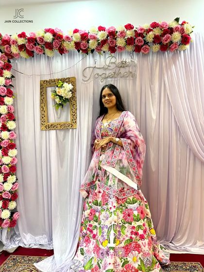 Another happy client in a beautiful floral lehenga, posing in front of a "Better Together" sign.