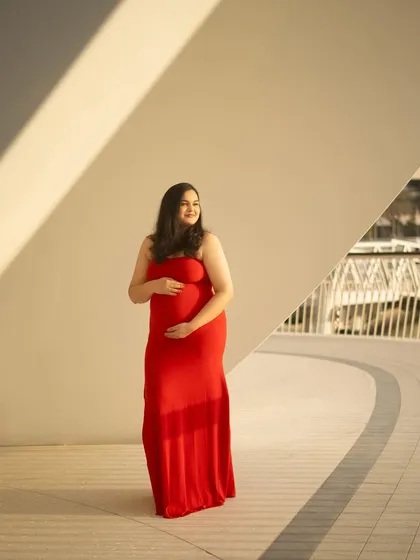 A simple and joyful outdoor portrait. The mom-to-be’s happy expression and the way she holds her bump convey a sense of peaceful anticipation.