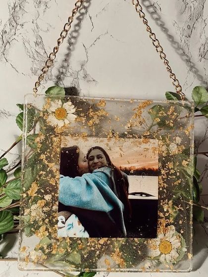 A simple and sweet way to display a favorite photo. This custom resin frame is filled with delicate dried flowers and gold flakes, perfect for preserving a cherished memory.