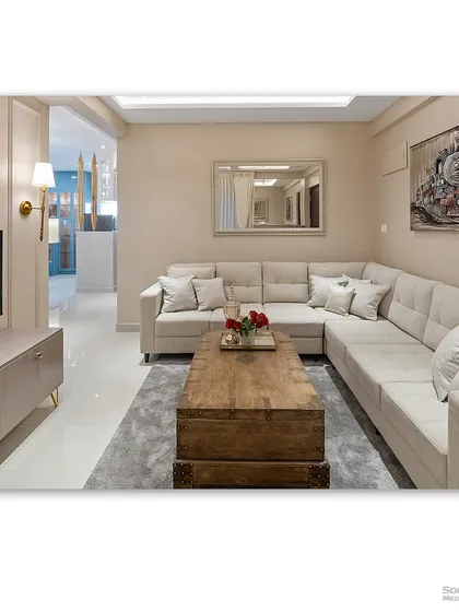 A comfortable and inviting living room with a large L-shaped sofa in a neutral beige tone. The vintage-style trunk used as a coffee table adds a unique and personal touch to the space.