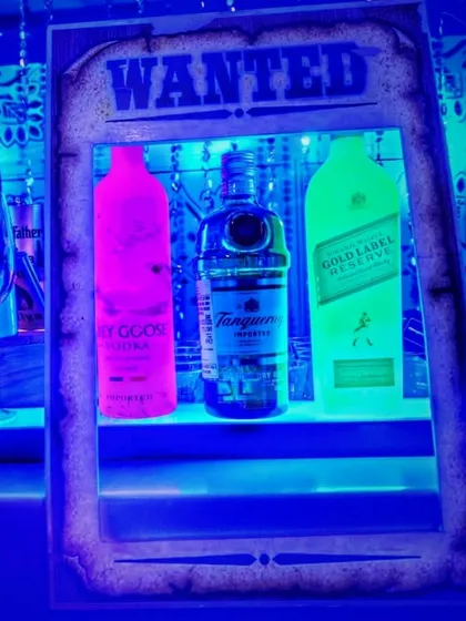 Setting the mood with a 'Wanted' poster display case. This custom prop uses blacklight to make the liquor bottles glow, adding a dramatic and edgy feel to the Bollywood theme.