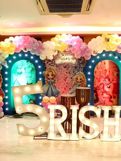 For a truly grand celebration, we designed this Disney Princess themed 5th birthday party. The setup includes multiple themed backdrops, character cut-outs, a sparkling shimmer wall, and large marquee letters spelling out the birthday girl's name.