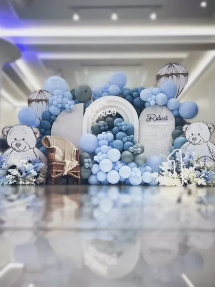 An elaborate teddy bear themed setup in shades of blue and white. The backdrop features large illustrated bears and a wicker chair for the birthday boy, creating a grand photo opportunity.