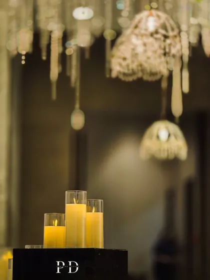 A beautifully blurred shot focusing on the candles, with the crystal chandeliers creating a soft, sparkling bokeh effect in the background. This highlights the romantic mood of the decor.