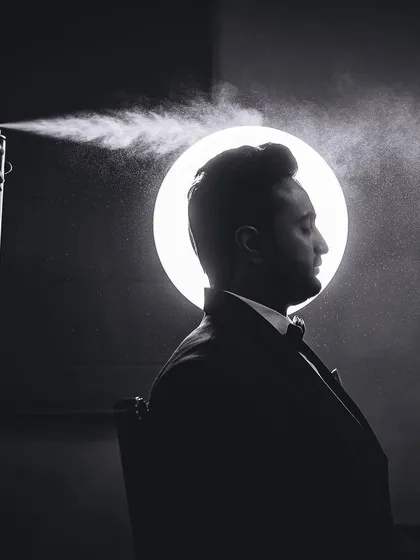 A creative, high-contrast portrait of the groom getting ready. We use dramatic lighting and unique angles to create artistic shots that add a touch of style and personality to your wedding gallery.
