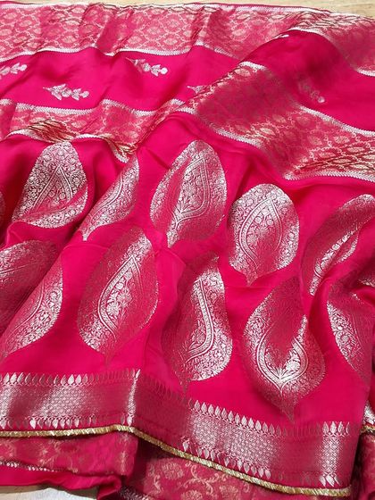 A vibrant pink silk saree with large silver zari paisley motifs. This is a classic Banarasi design that exudes timeless elegance and is perfect for weddings.