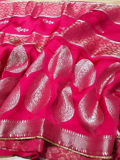 A stunning rani pink soft silk saree with large silver paisley butas. The fine zari border adds to its festive appeal, making it perfect for weddings and celebrations.
