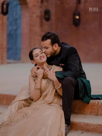 A sweet, candid moment as Dheeraj kisses Navdeep's cheek. This intimate photo, set against the rustic stone steps of a palace-like location, beautifully blends romance with a grand setting.