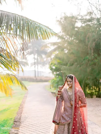 A bride walks along a path in Goa, the morning sun filtering through the palm trees, creating a soft, dreamy portrait.