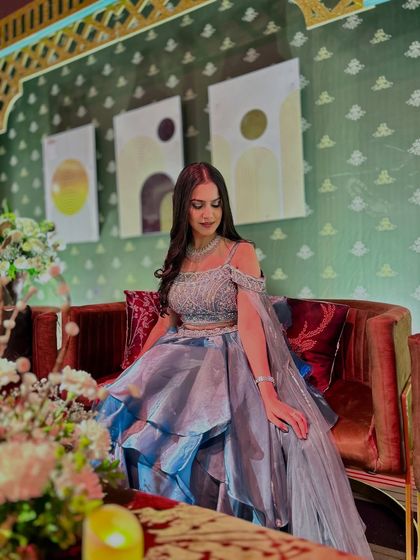 Seated on a plush red sofa, this shot highlights the contrast of colors and the beautiful texture of the gown.