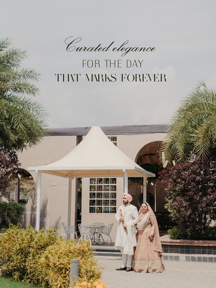 Curated elegance for the day that marks forever. This wide shot showcases the beautiful harmony between the couple's pastel wedding outfits and the serene outdoor setting.