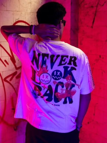 A shot focusing on the back of a graphic tee, lit with intense pink light against a graffiti wall. This highlights the design details that are crucial for streetwear brands.