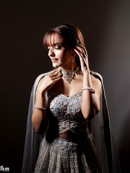 A stunning bridal portrait using dramatic side lighting. The light beautifully sculpts her features and highlights the intricate details of her jewelry and gown, creating a moody and elegant look.