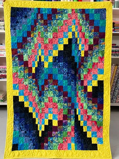 A bright and cheerful Bargello quilt with a dynamic pattern in blues, pinks, and yellows.