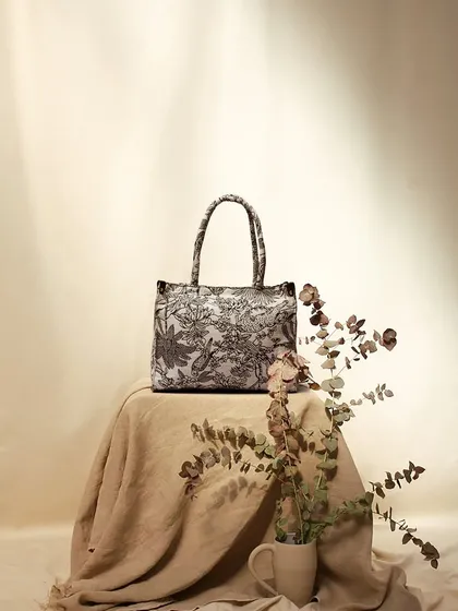 An earthy, rustic still life featuring a patterned tote bag. The use of natural linen fabric and dried eucalyptus creates a soft, organic, and sophisticated mood.
