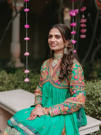 A poised and elegant portrait of the mother of the bride, showcasing her beautiful embroidered outfit and the soft, glowing makeup.