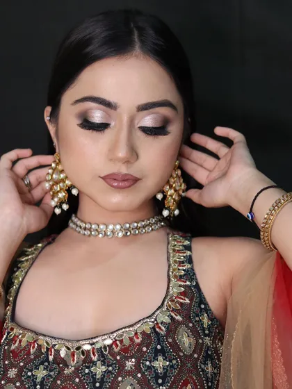 The model adjusts her earrings, giving a candid feel to this beautiful shot of the cut-crease makeup.