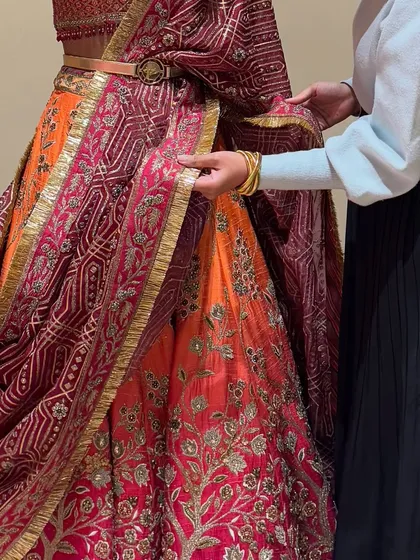 A close-up of me adjusting the drape of a stunning bandhani lehenga. Perfecting the fall of the dupatta is a crucial step in completing the bridal look.
