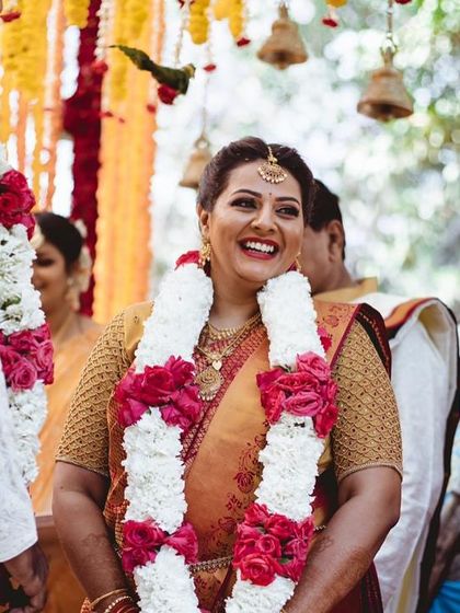 The joy of a wedding day. This candid shot captures a happy moment. The bride's makeup is natural and glowing, perfect for an outdoor South Indian ceremony.